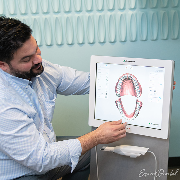 male dental professional looking over dental records on screen
