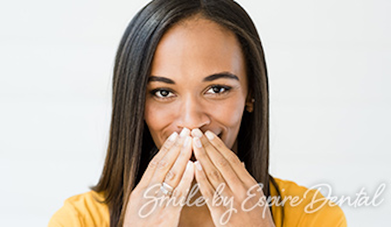 black woman with straight hair smiling with hands covering her mouth
