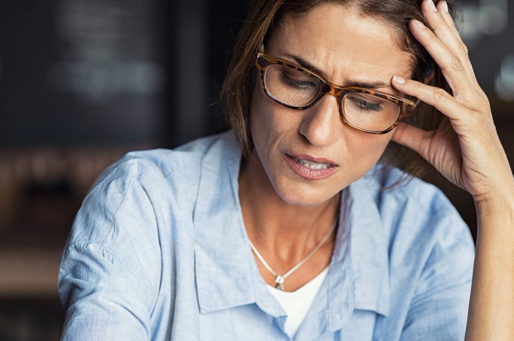 brunette woman in glasses struggling with headache
