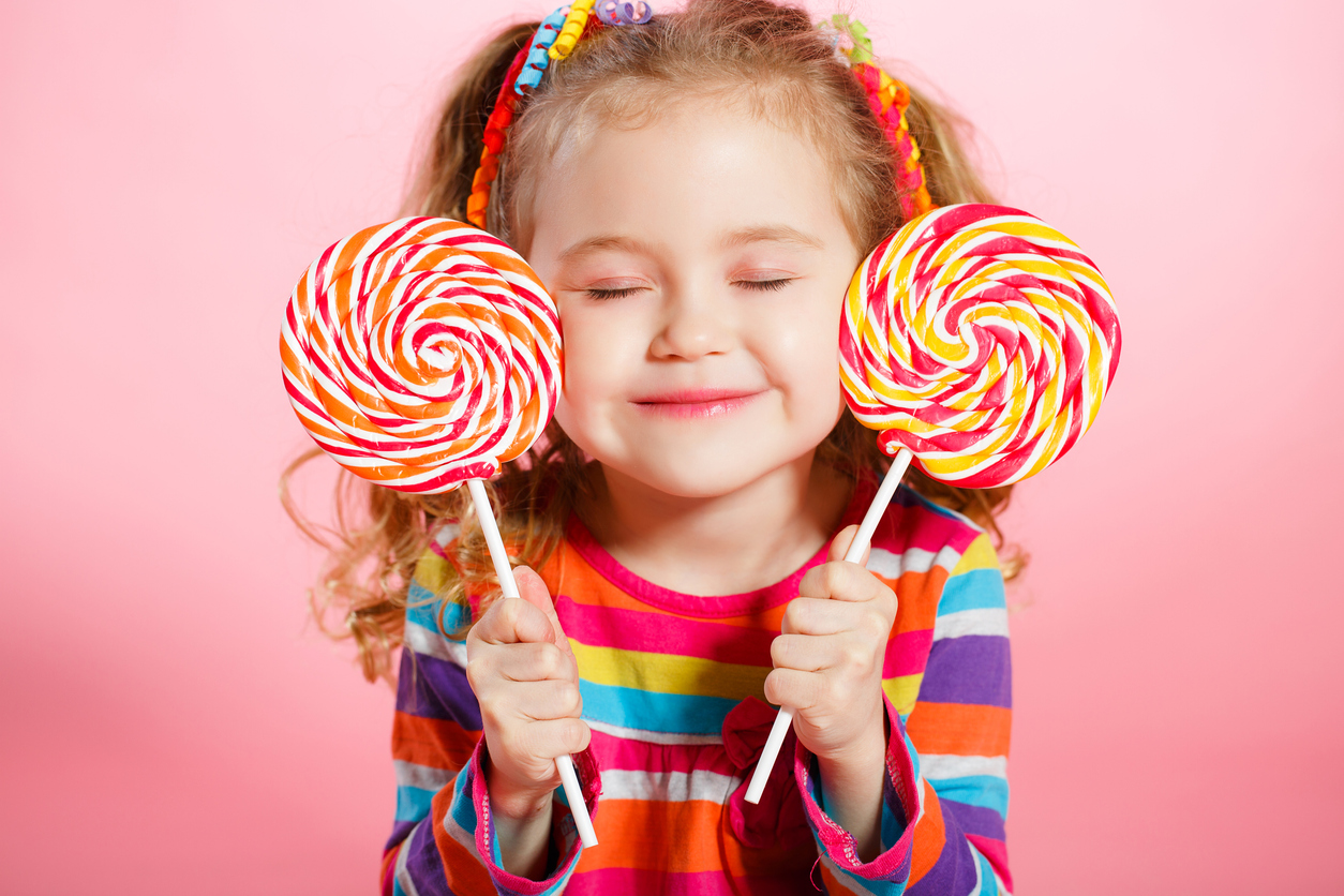 blonde girl smiling with two lollipops in each hand