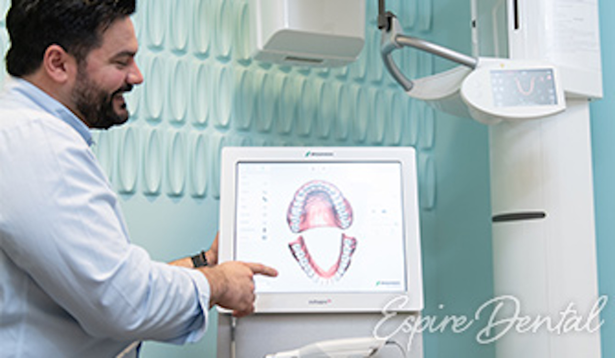 dentist pointing at an image of teeth on a computer screen