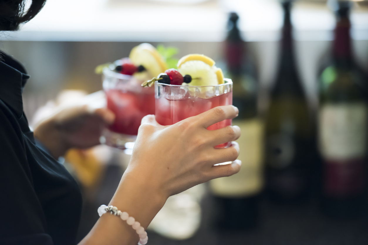 nærbillede af en kvindes hånd, der holder en rød cocktail