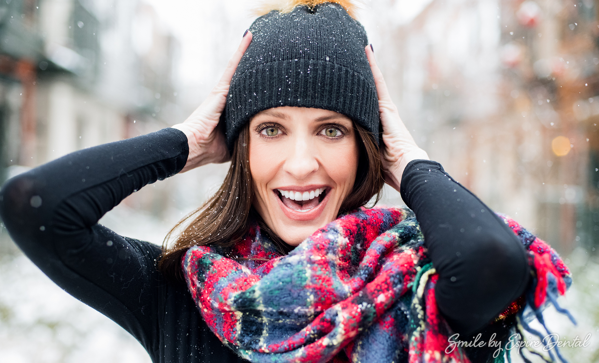 smiling brunette woman in hat and scarf in the snow
